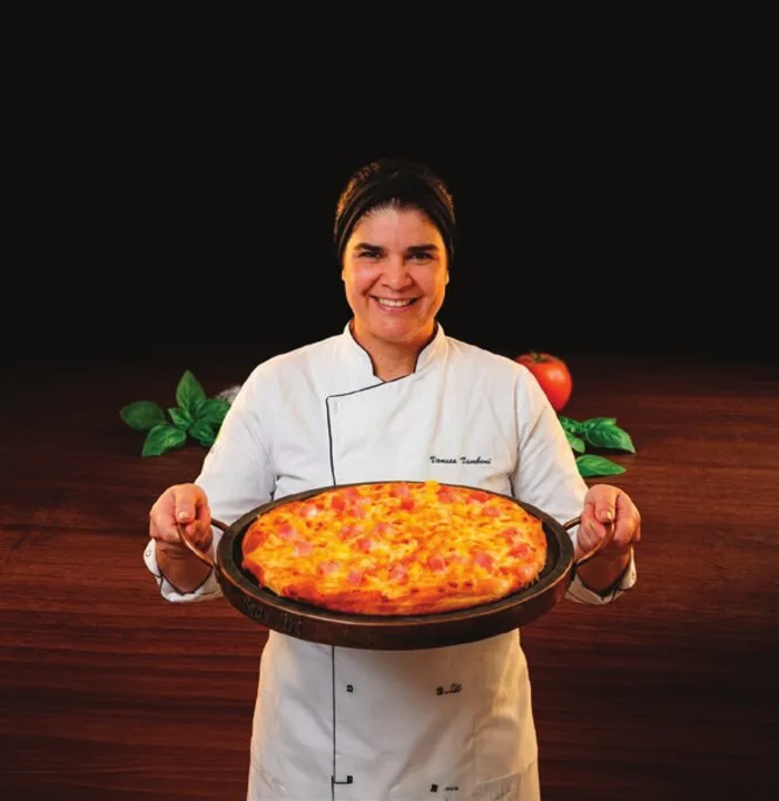 Chef Vanusa Tambani segurando uma pizza na forma